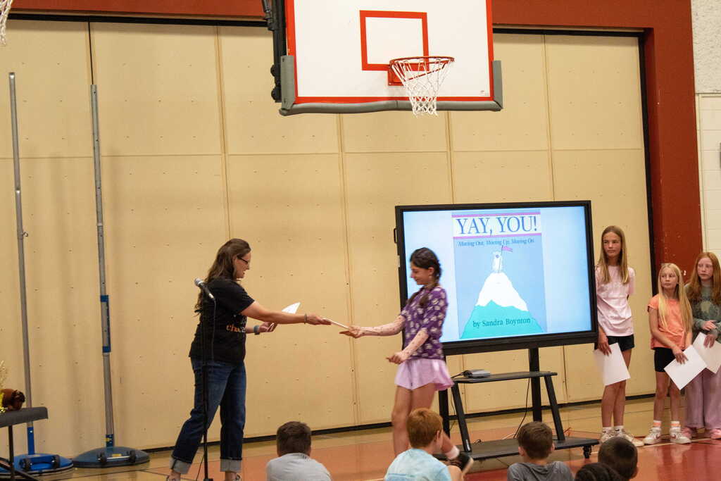 Female teacher handing young girl a certificate