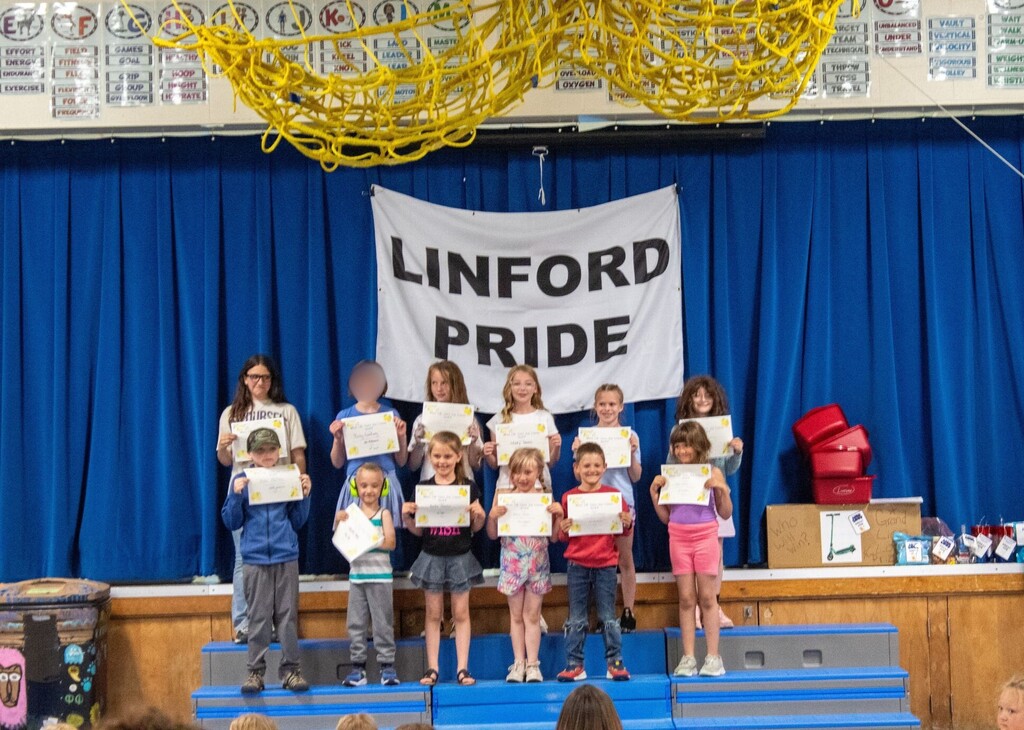 Group of students standing on stage smiling holding certificates