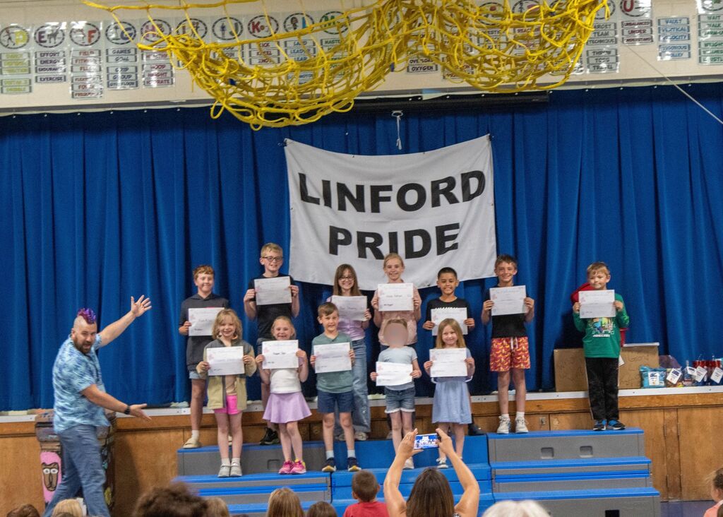 Group of students standing on stage smiling holding certificates