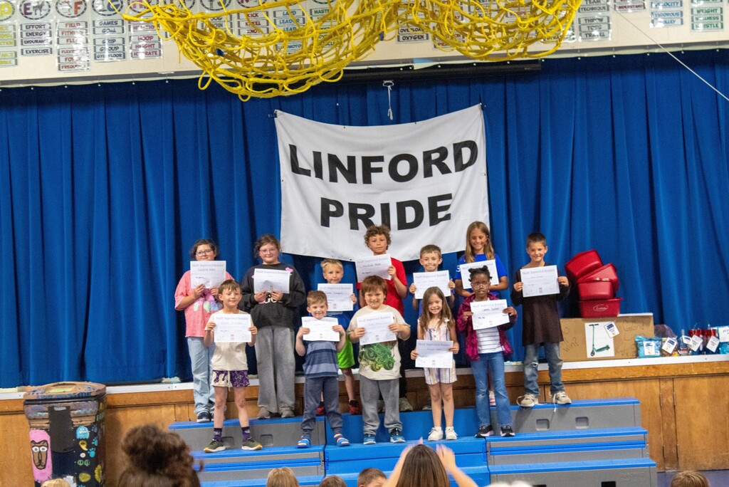 Group of students standing on stage smiling holding certificates