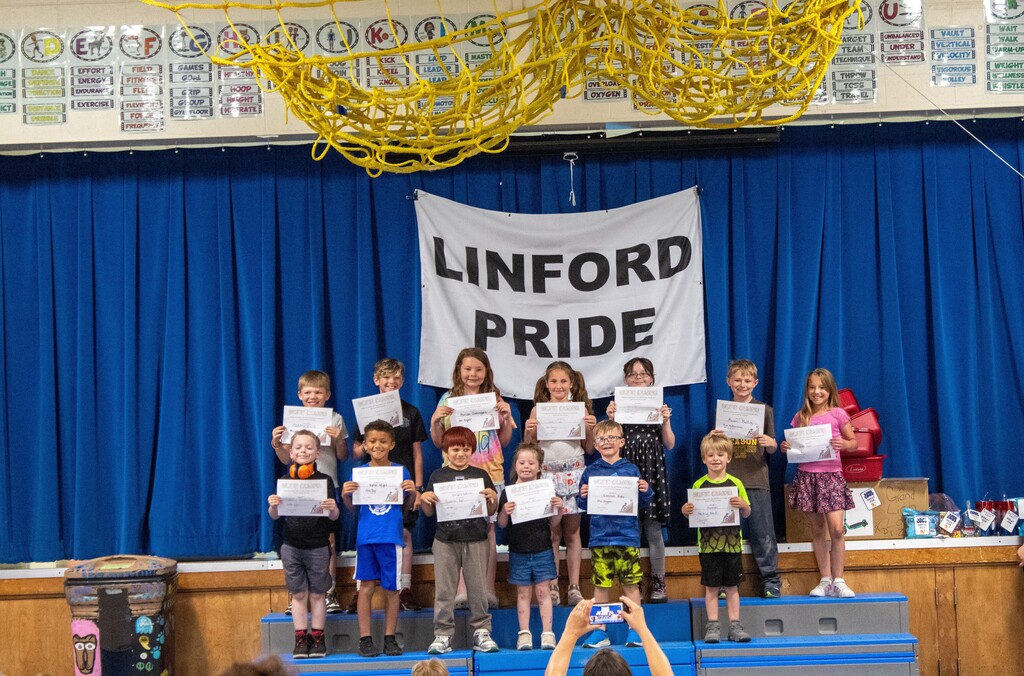Group of students standing on stage smiling holding certificates