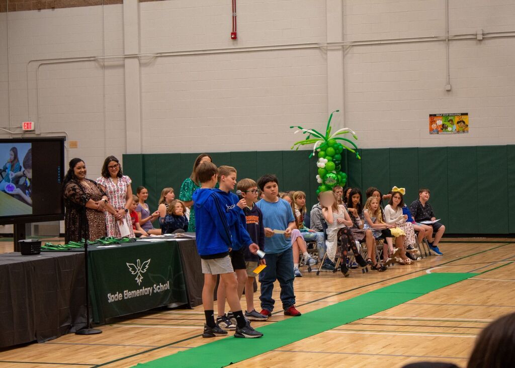 Student standing to receive award in front of peers, staff,  and family