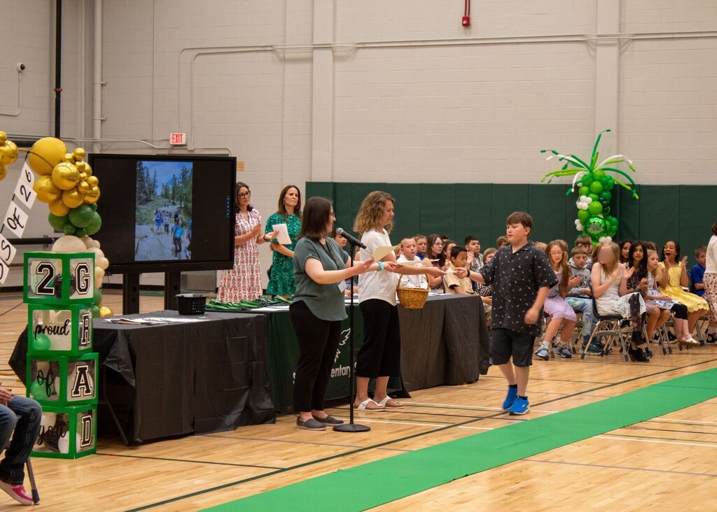 Student standing to receive award in front of peers, staff,  and family