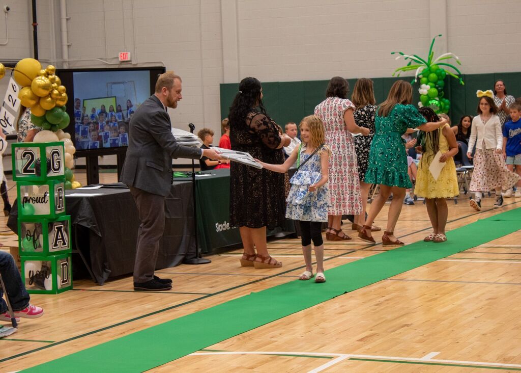 Student standing to receive award in front of peers, staff,  and family