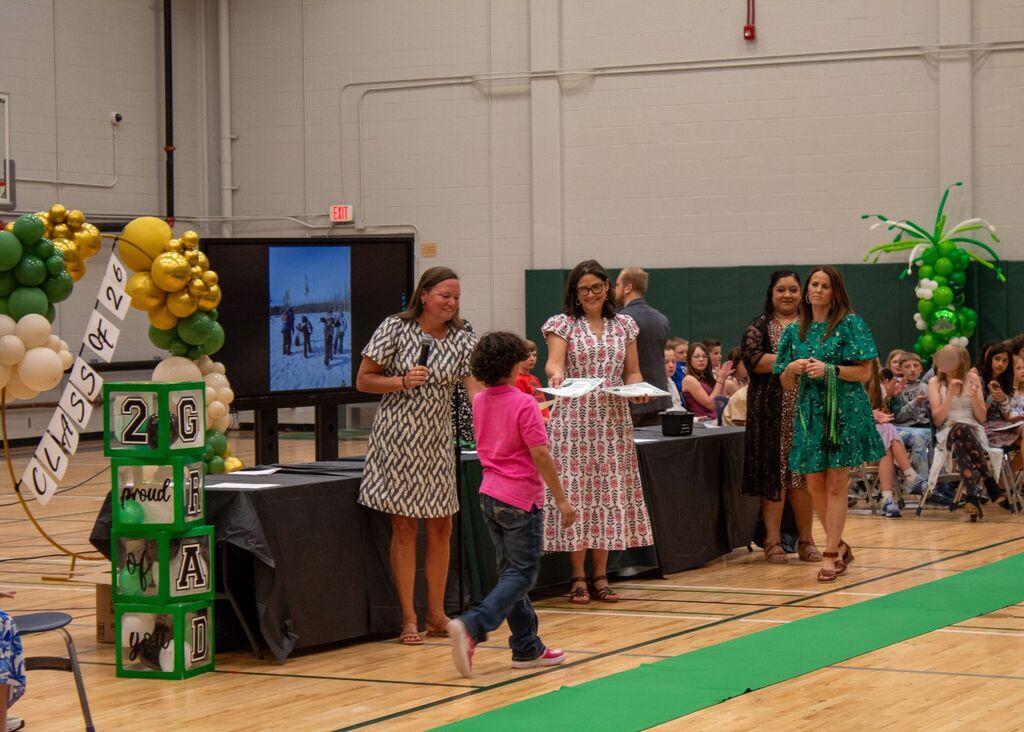 Student standing to receive award in front of peers, staff,  and family
