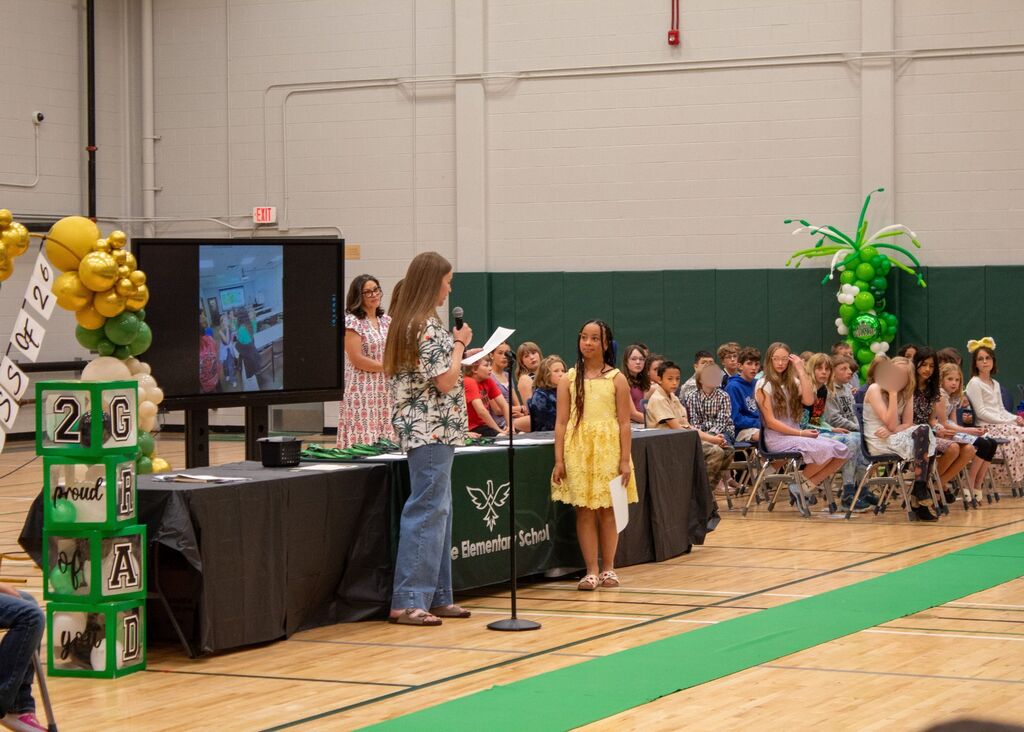 Student standing to receive award in front of peers, staff,  and family