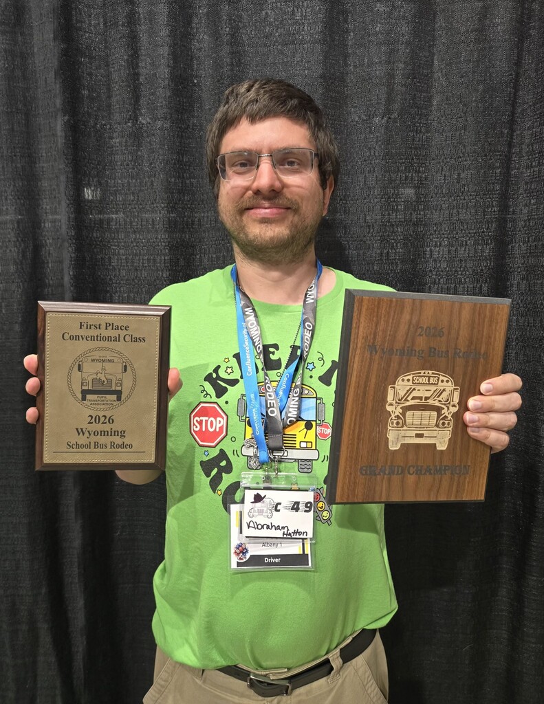 Man with brown hair in a green t-shirt holding two brown plaques