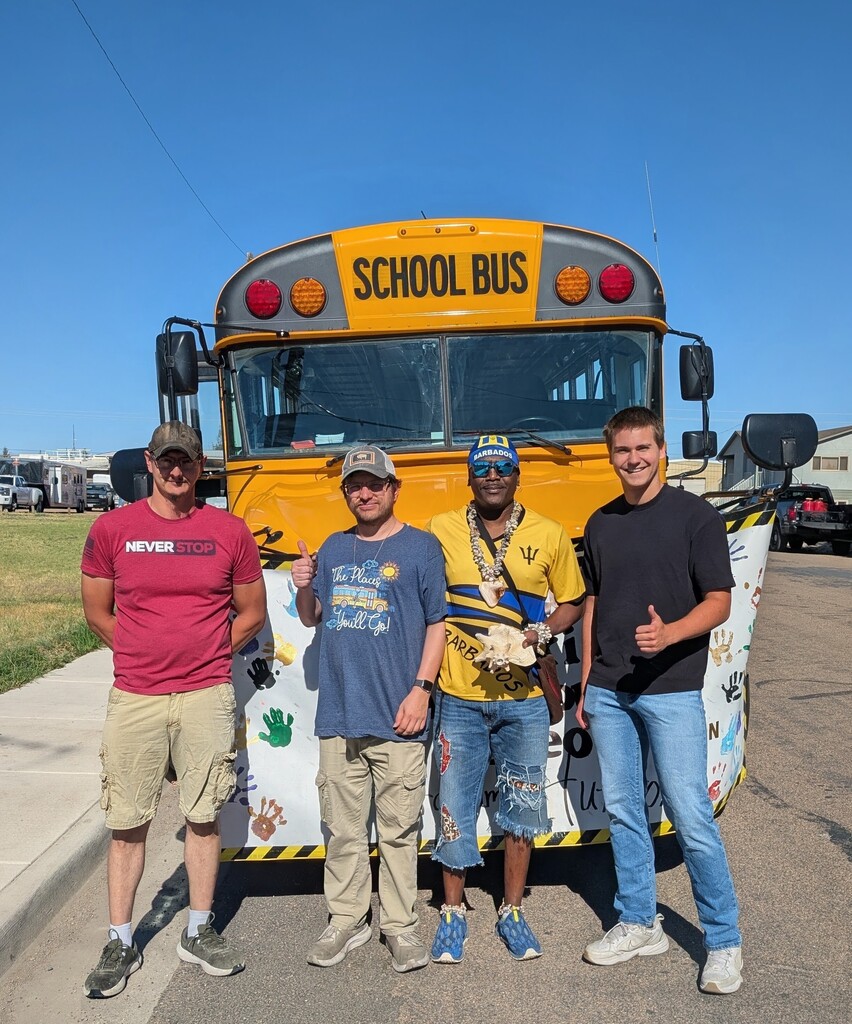 Four men standing in front of a school bus