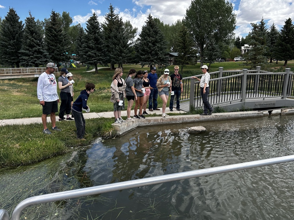 Group of students standing around a pond preparing to collect water