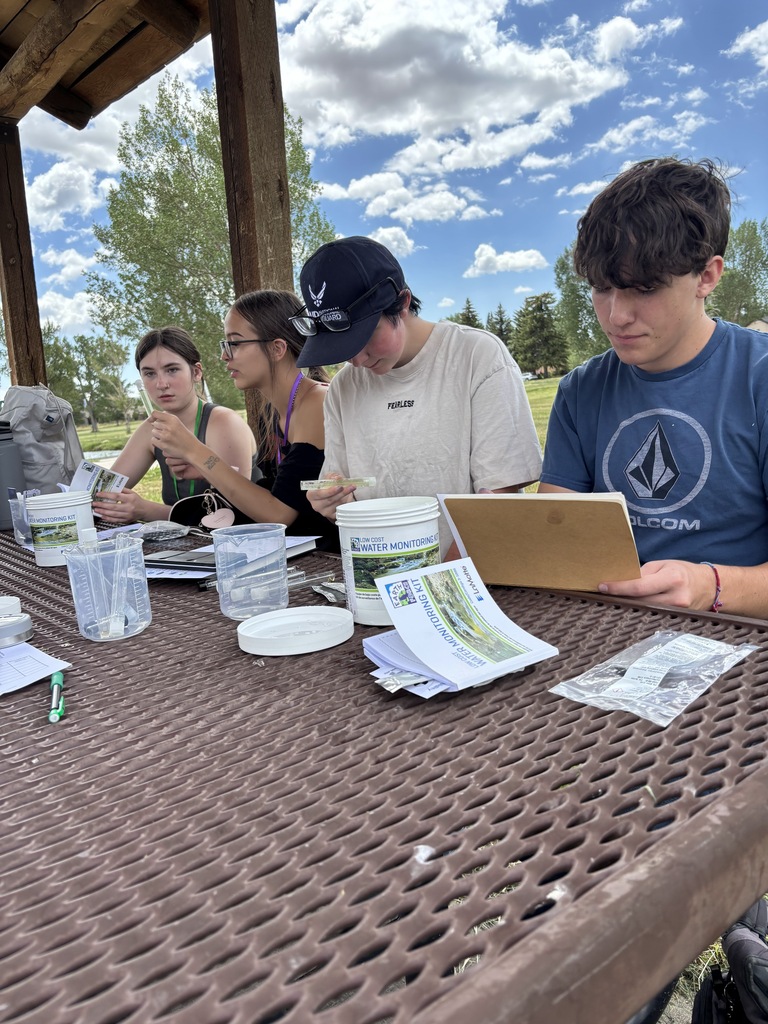 Four students working with water samples at a picnic table