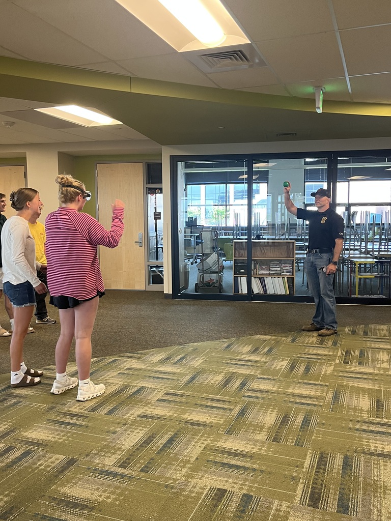 Two female students with goggles on talking to an officer
