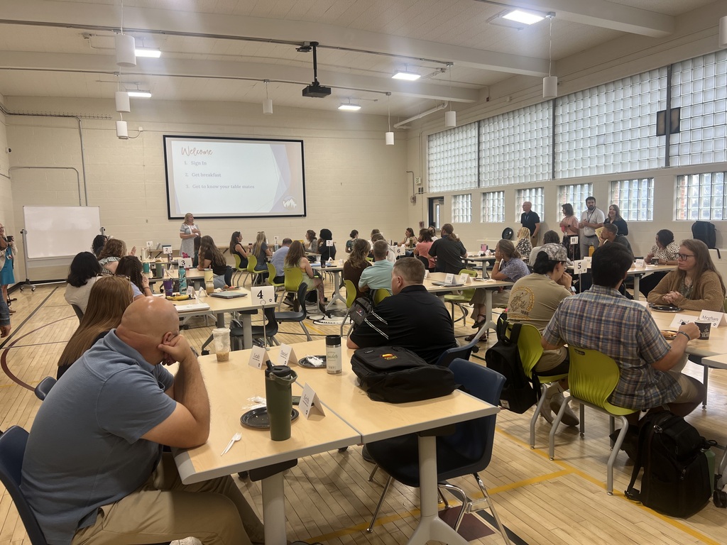 Group of men and women sitting around tables in a gym