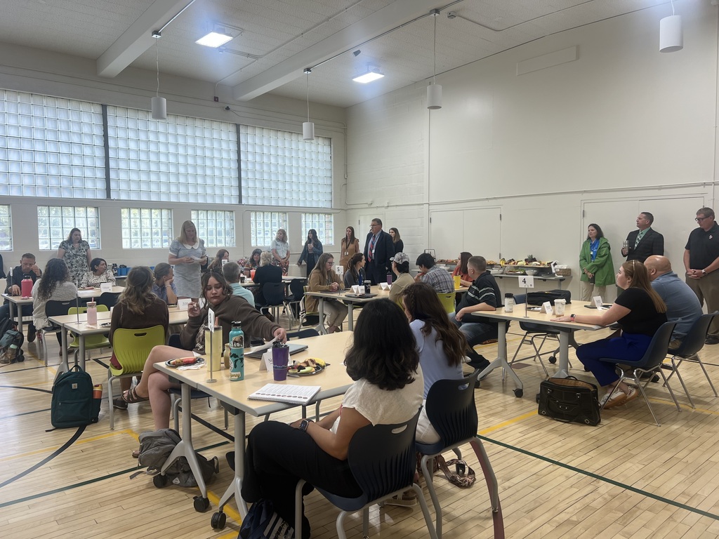 Group of men and women sitting around tables in a gym