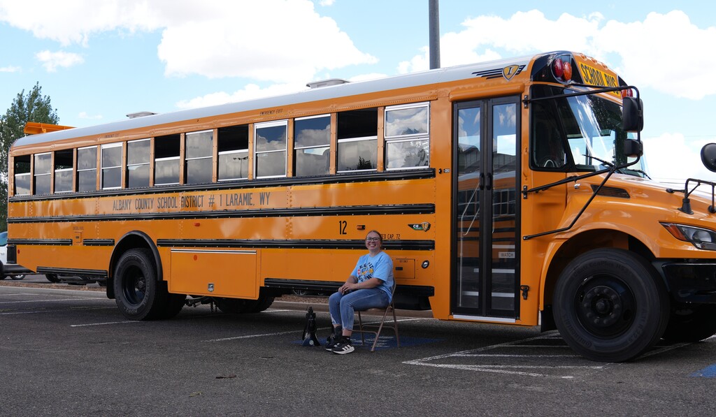 woman sitting outside a school bus on a chair