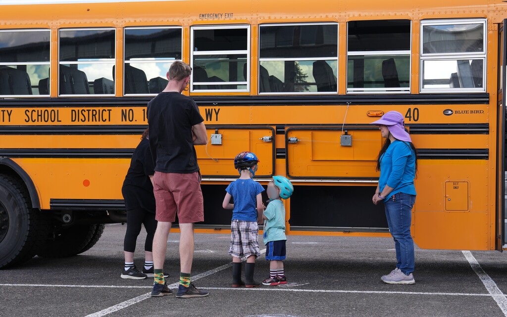 Students standing with parent looking at school bus