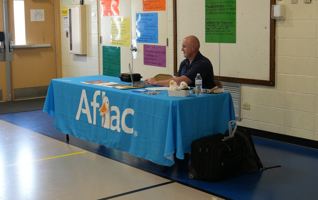 Man sititng at a table with an aflac table cover