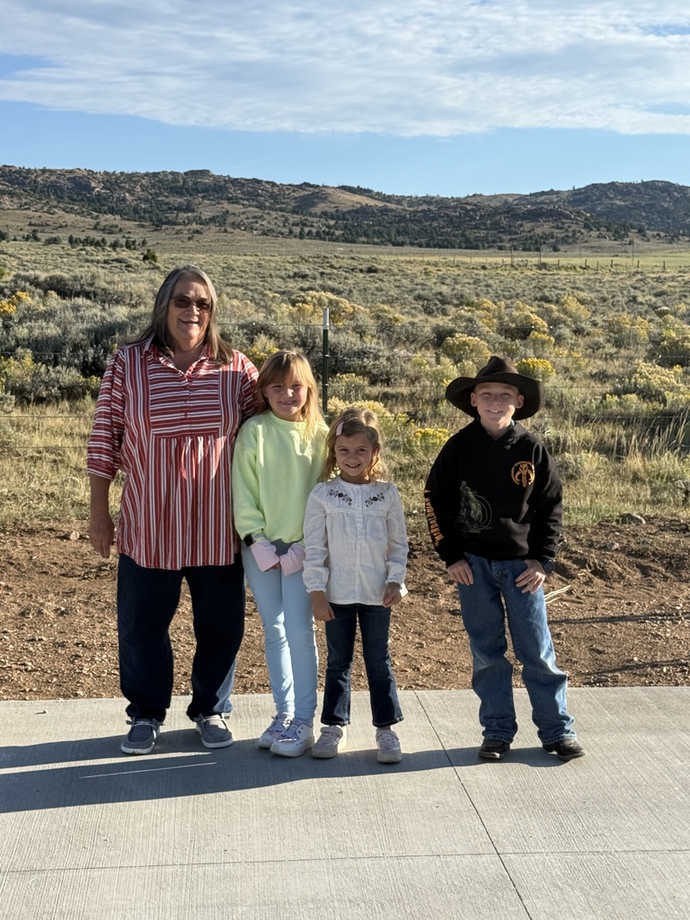 Three elementary students standing next to teacher