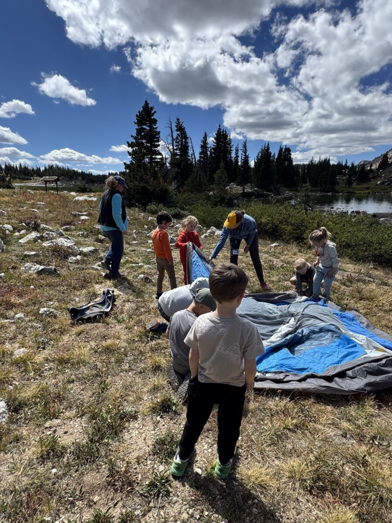 students helping teacher set up a tent