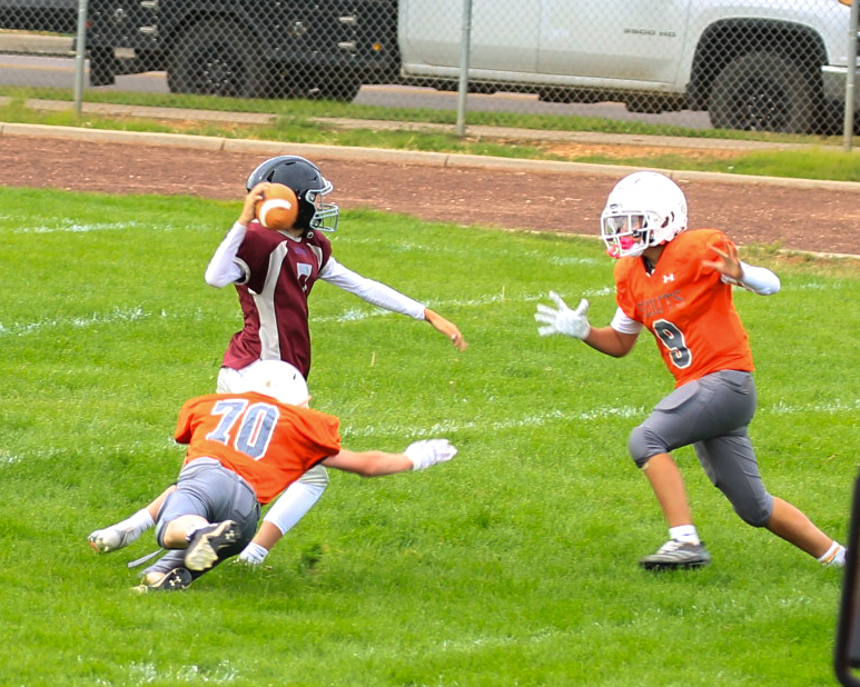 Two students in oragne trying to catch student in red jersey