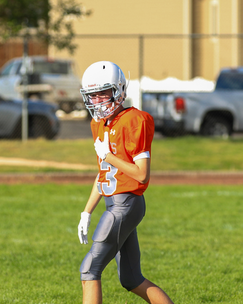 Student in orange football jersey walking the field