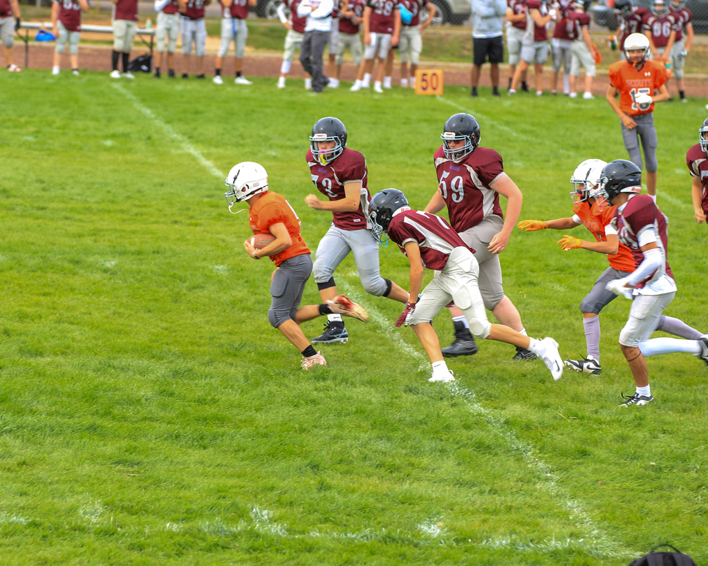 Students in oragne and red jerseys playing football