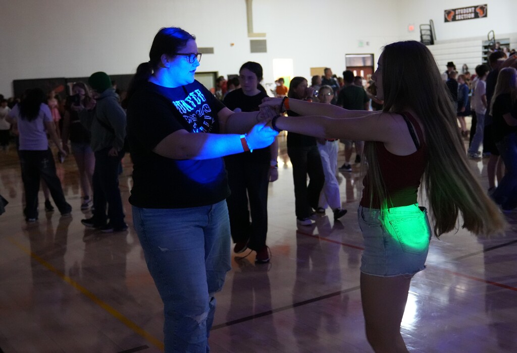 two girls swing dancing in a gym