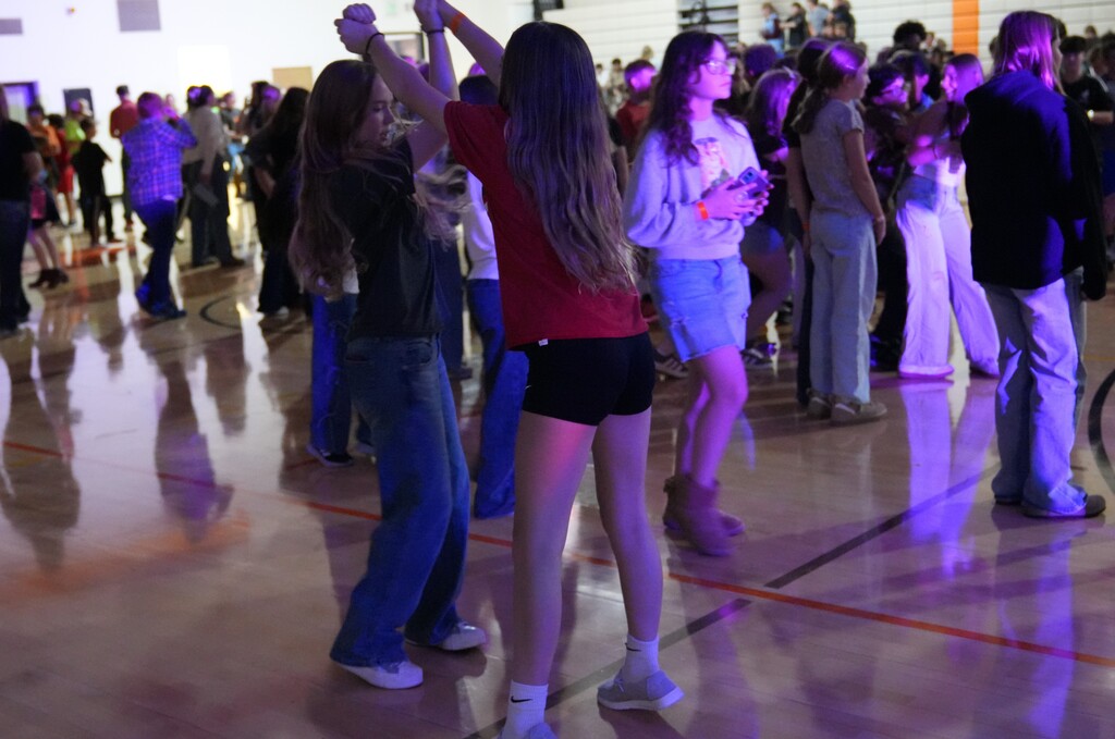 two girls swing dancing in a gym