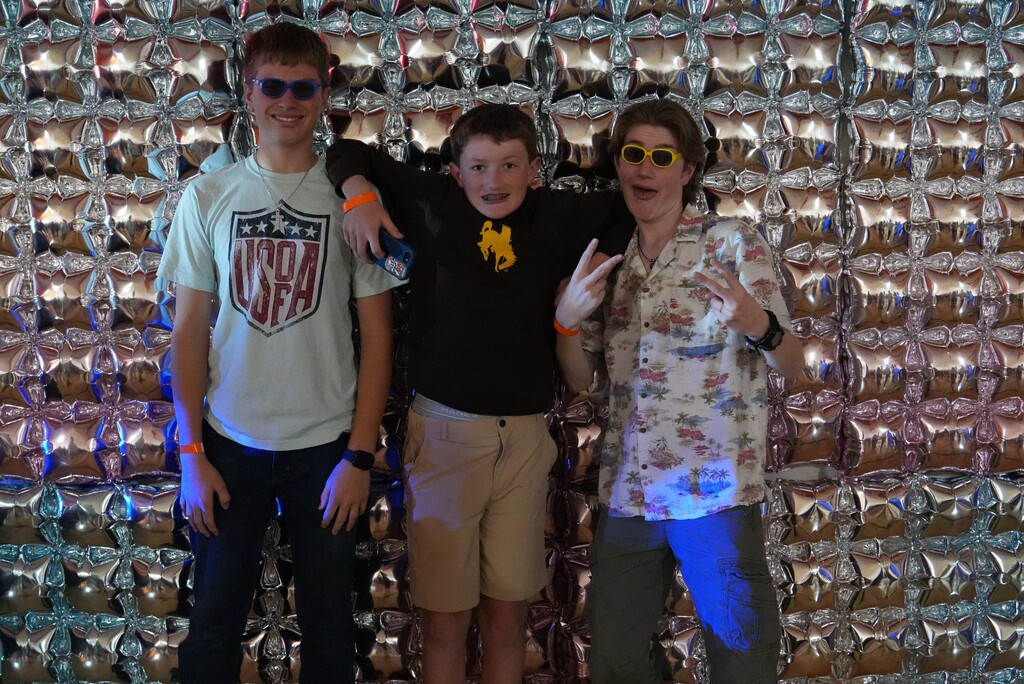 Three boys standing agaisnt a disco wall