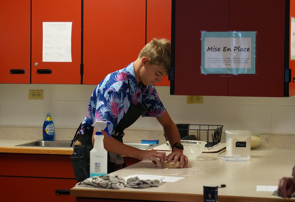 Young man with blonde hair shaping dough