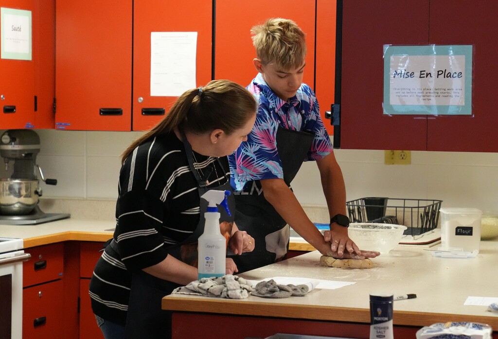 Teacher guding student through baking process