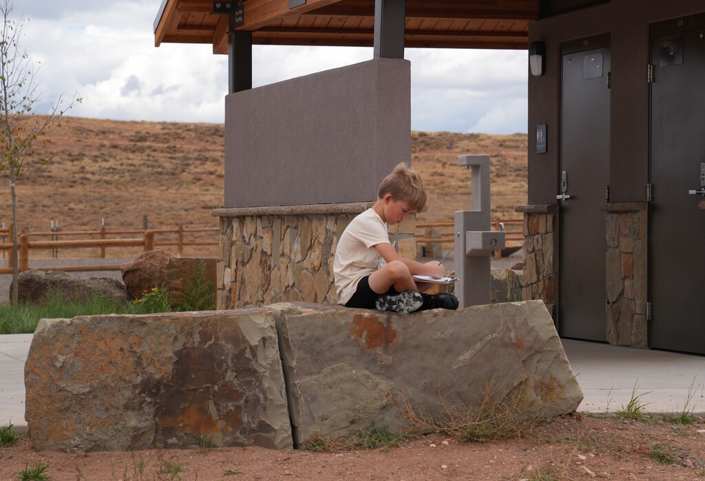 Young boy sitting on a rock drawing his surroundings