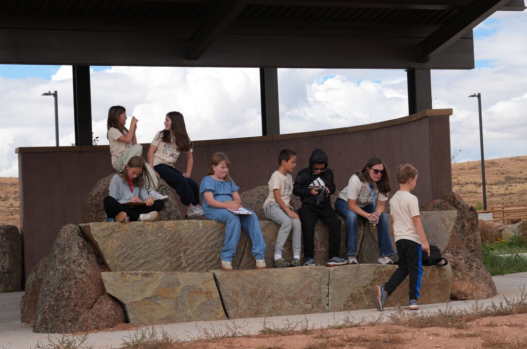 Students sitting on a rock cpaturing their surroundings