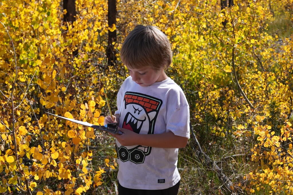 Boy in a white shirt writing on a clipboard