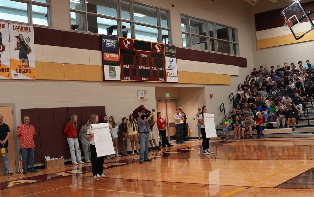 Group standing against a wall while two students hold up posters with words