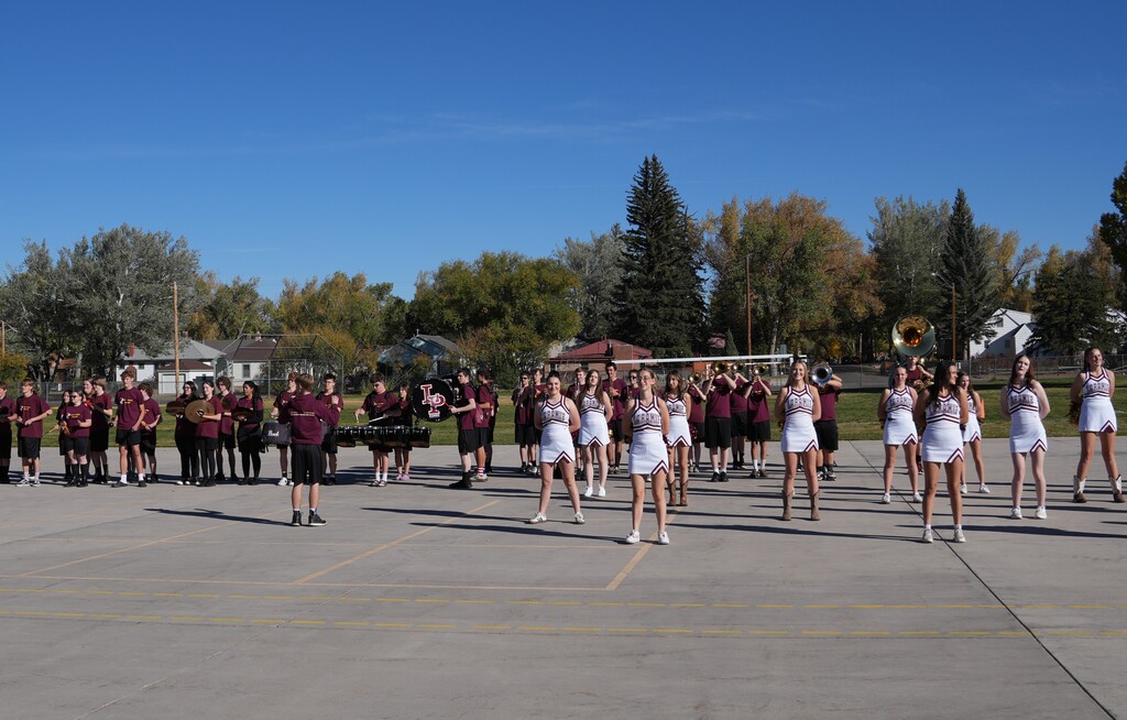 Cheerleaders and band members standing on a concrete pad