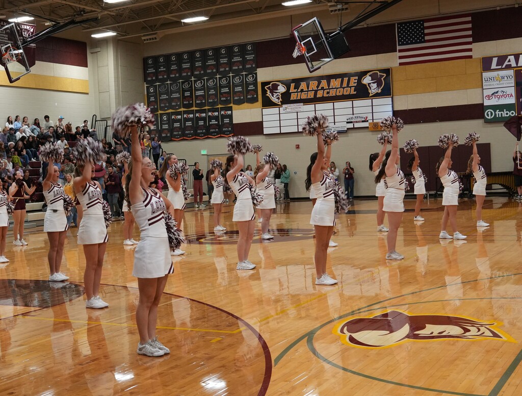 Cheerleaders standing in the gym with poms