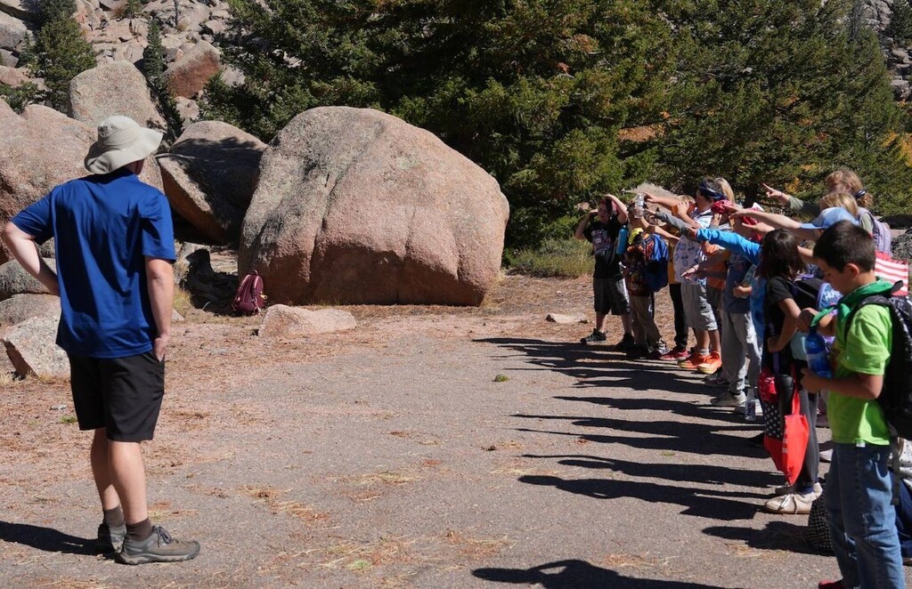 students lined up by big rocks pointing 