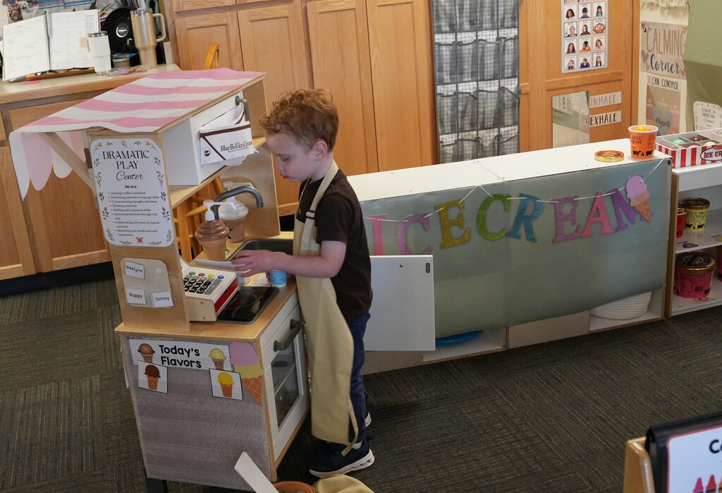 Boy in an apron playing with a cash register