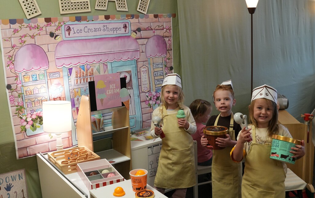 Three students wearing aprons and hats posing with ice cream toys