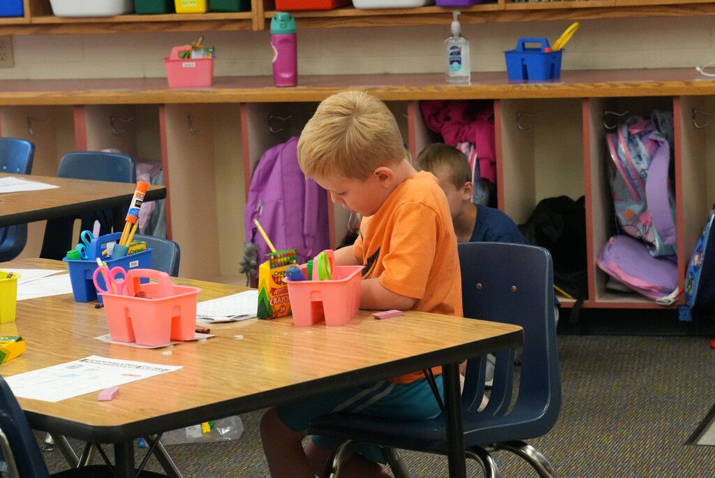 Young boy sitting at desk writing on paper
