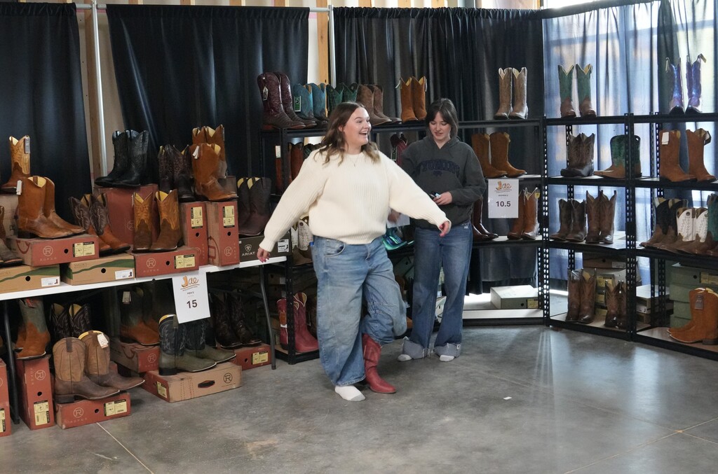 Girl in jeans and white sweater trying on cowboy boots
