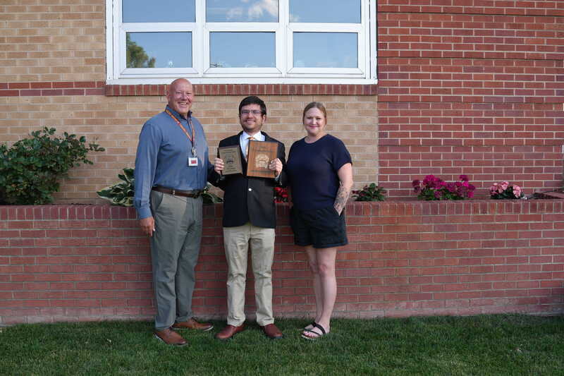 Three adults standing together holding champion plaques