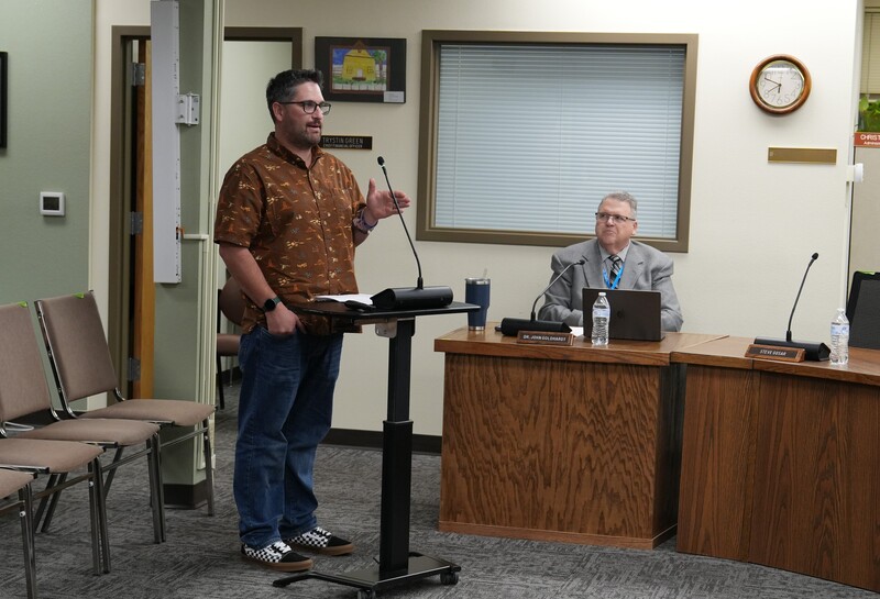 Man in brown shirt standing at a podium presenting
