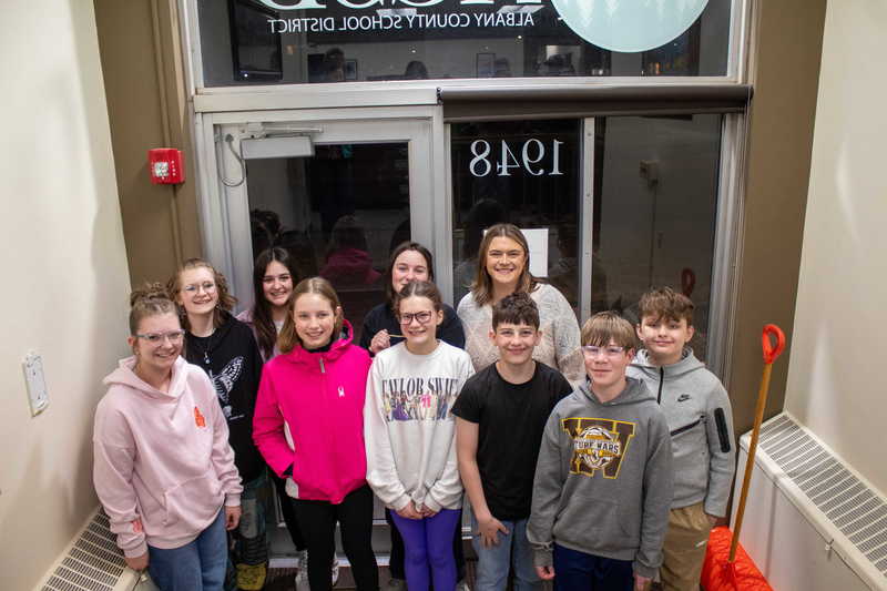 middle school students posing in doorway with teacher