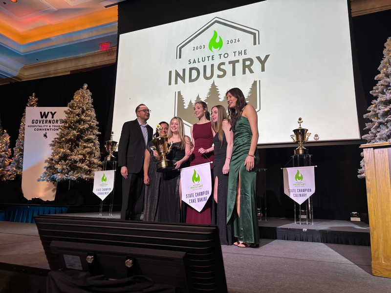 middle school students posing in doorway with teacher