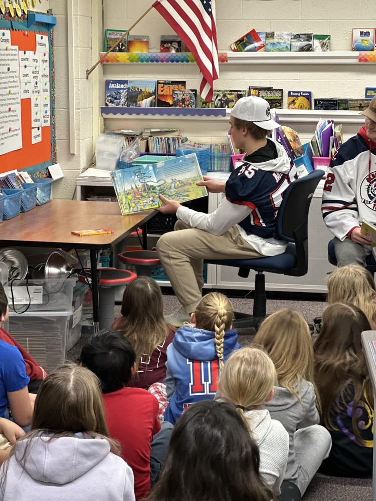 High school athletes reading to elementary students. 