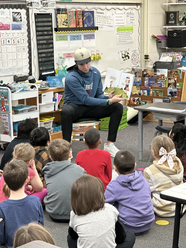 High school athletes reading to elementary students. 