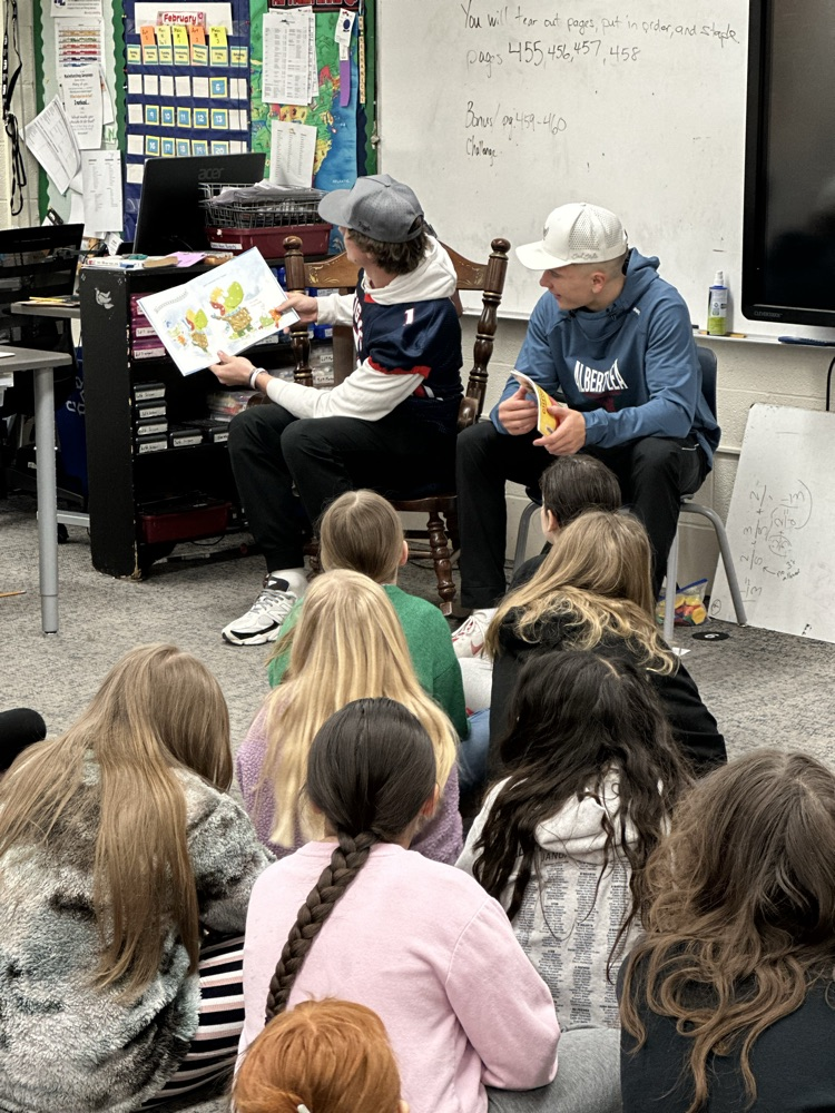 High school athletes reading to elementary students. 