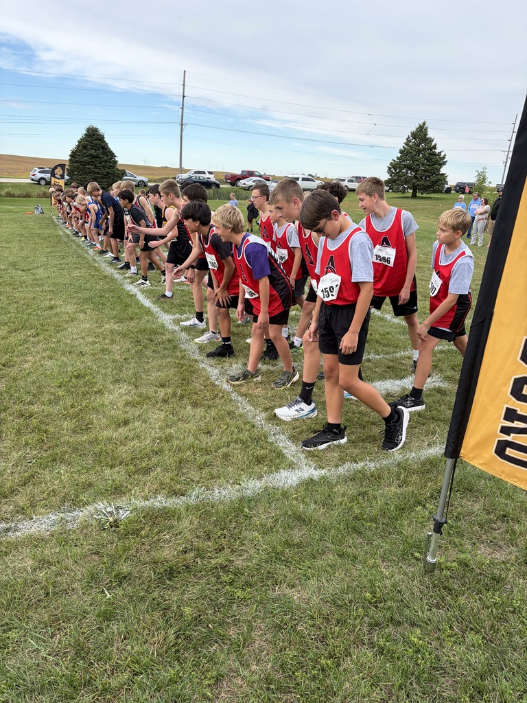 A group of children in matching uniforms stand in a line on a grassy field.