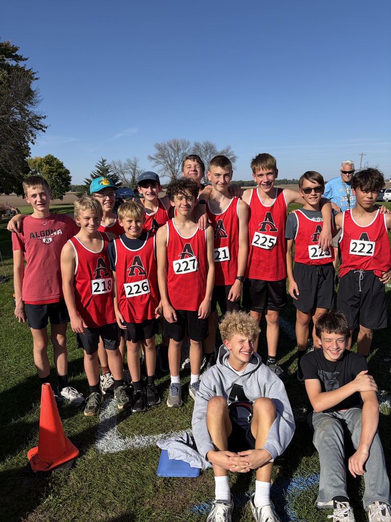 A group of young athletes in red shirts pose for a photo on a grassy field. Numbers 215, 226, and 227 are visible.